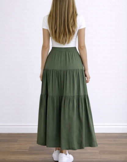 Back view of woman wearing a white top and green High Waist Tiered Hem Maxi Skirt on a plain background.