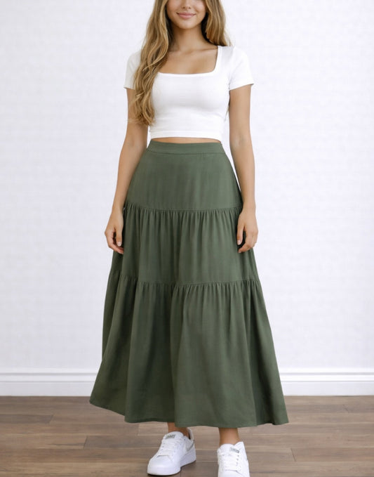 Woman wearing a white top and green High Waist Tiered Hem Maxi Skirt on a plain background