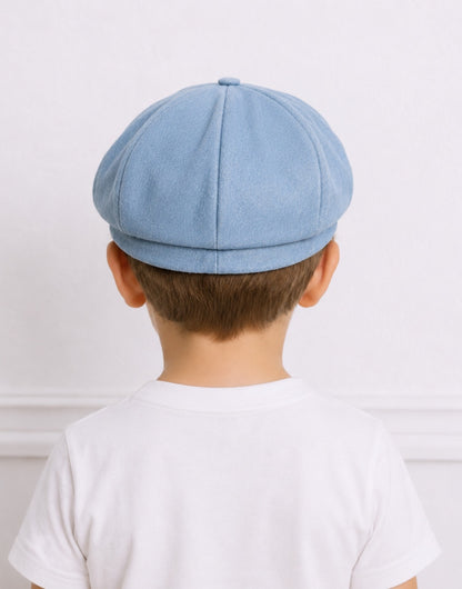 Back view of a young boy wearing a light blue denim Baker Boy Cap with a white crew neck tee shirt.