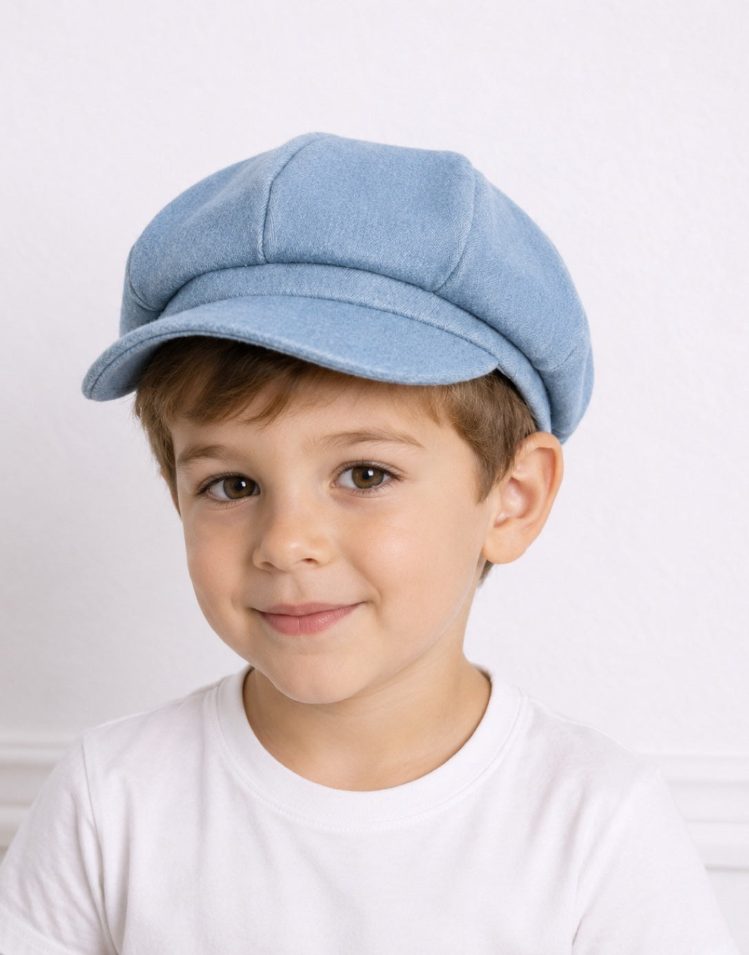 Young boy wearing a light blue denim Baker Boy Cap with a white crew neck tee
