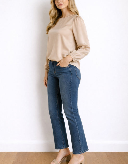 Side view of woman wearing a beige Lantern Sleeve Blouse and blue jeans against a white background