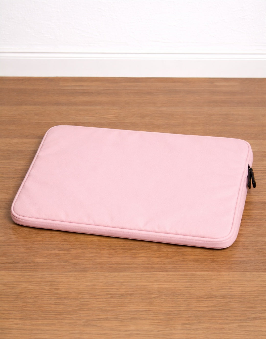 Back view of pink Laptop Bag on a wooden surface with a white background.