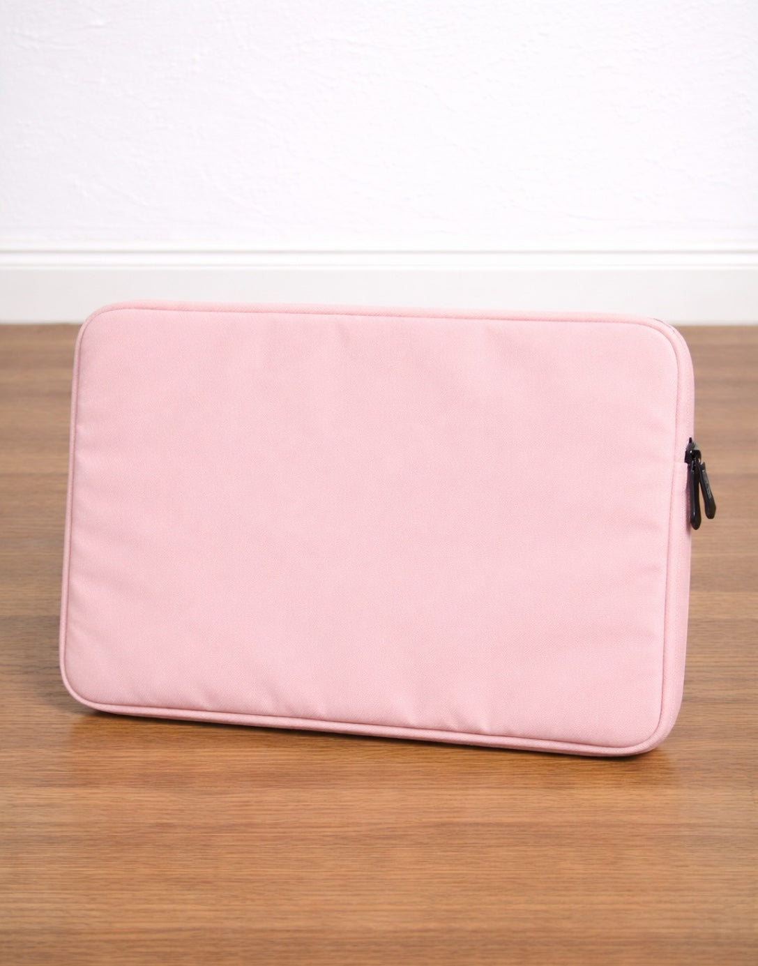 Side view of pink Laptop Sleeve on a wooden surface with a white background.