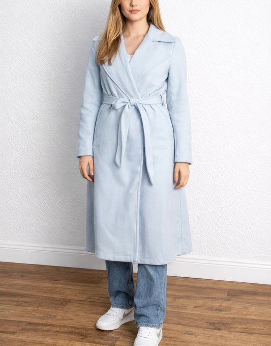 Woman wearing a light blue Long Belted Coat standing against a white wall.