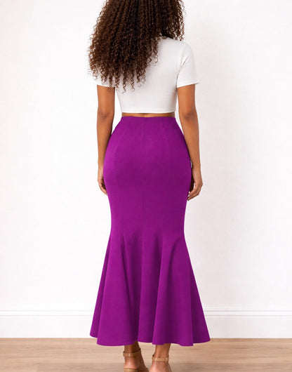 Back view of woman wearing a white top and purple Mermaid Skirt on a plain background.
