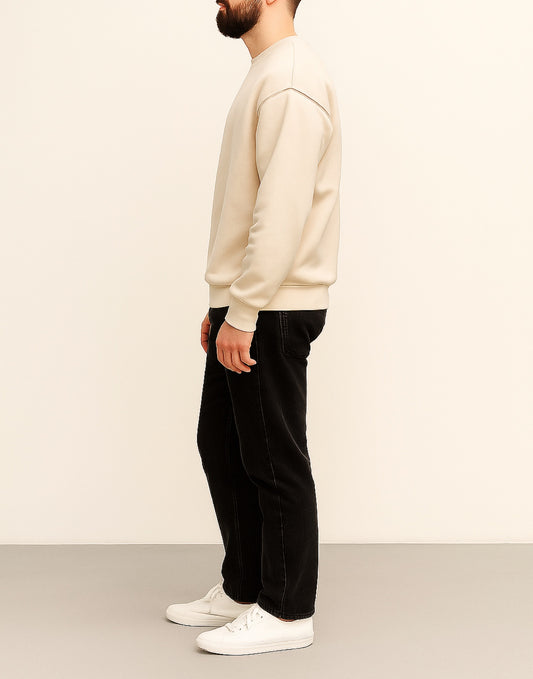 Side view of man wearing a beige sweater and black pants against a white background