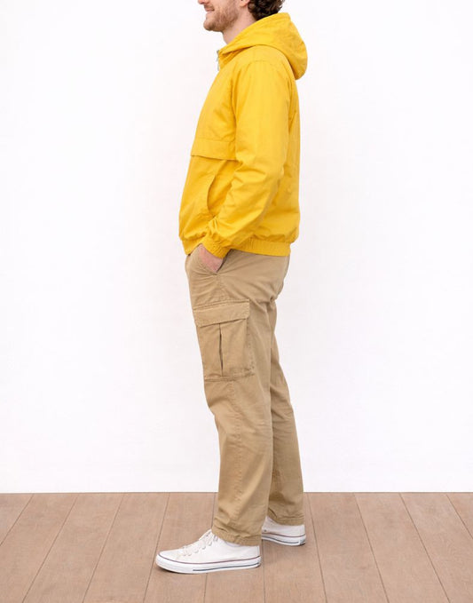 Side view of person wearing a yellow hooded Windbreaker Jacket and beige cargo pants against a white background.