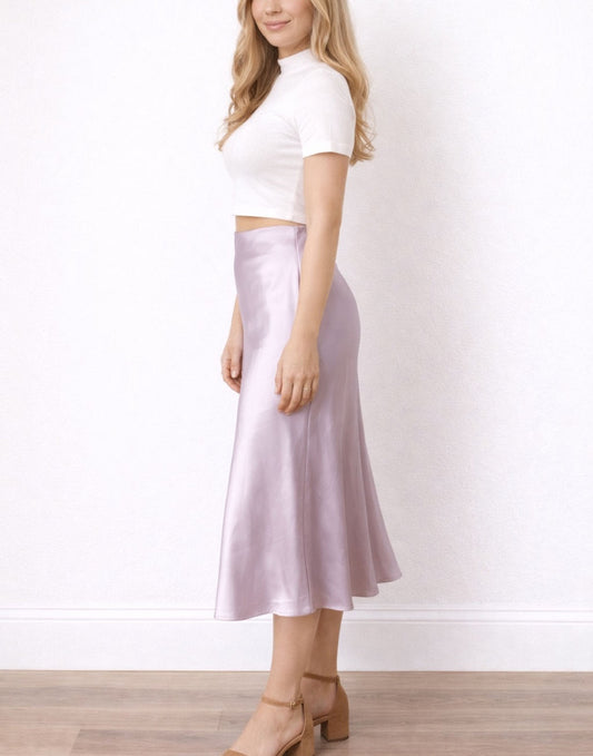 Side view of woman wearing a white crop top and purple satin Midi Slip Skirt on a wooden floor.