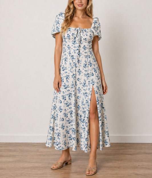 Woman wearing a floral Milkmaid Front Tie Maxi Dress with a slit on a plain background.