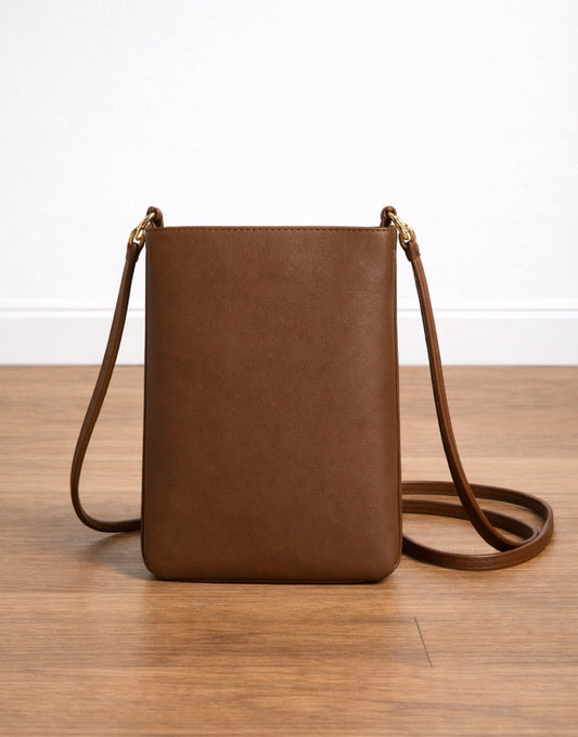 Brown leather Mini Crossbody Bag on a wooden surface with a white background