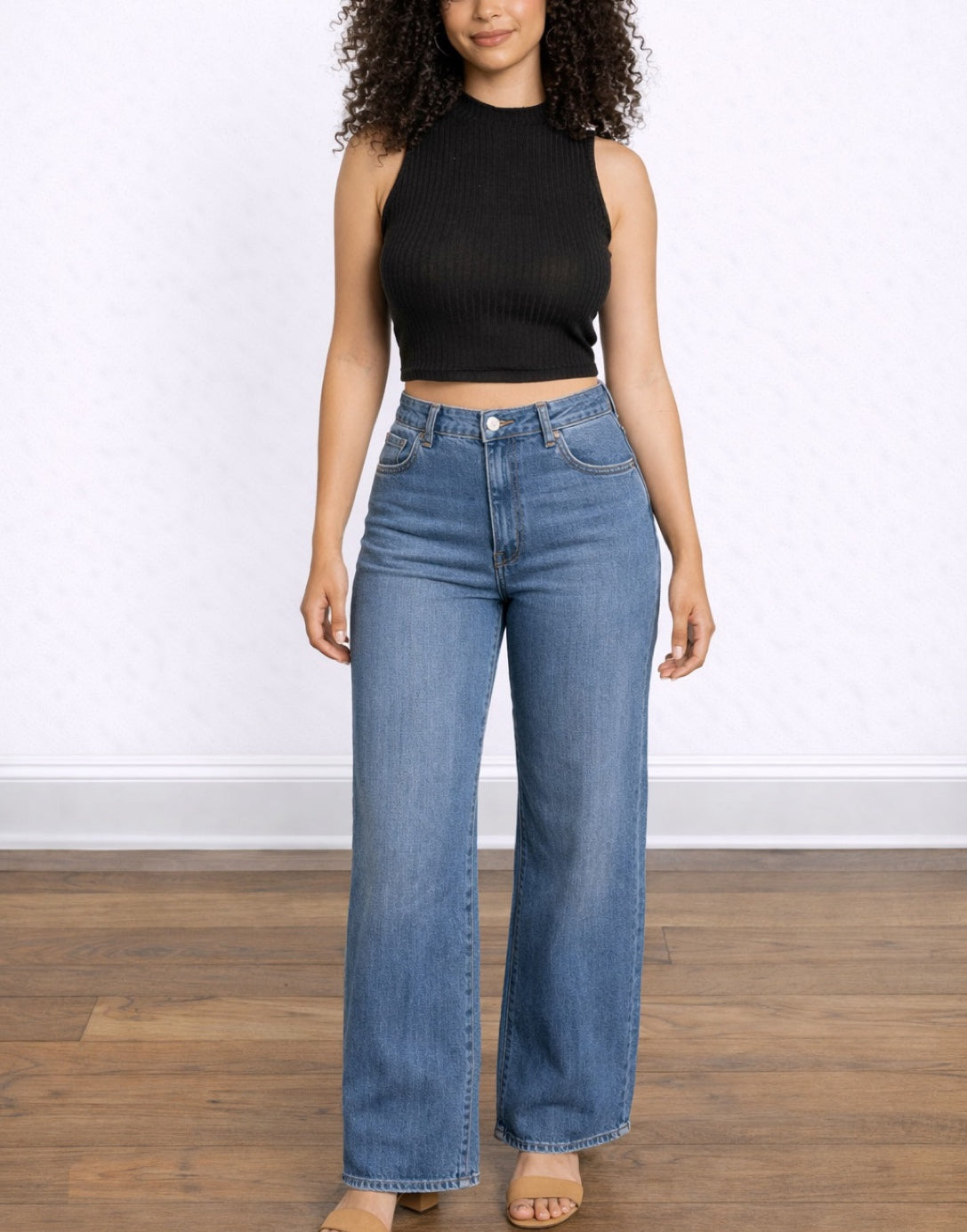Woman wearing blue jeans and a black Mock Neck Crop Tank Top on a white background.