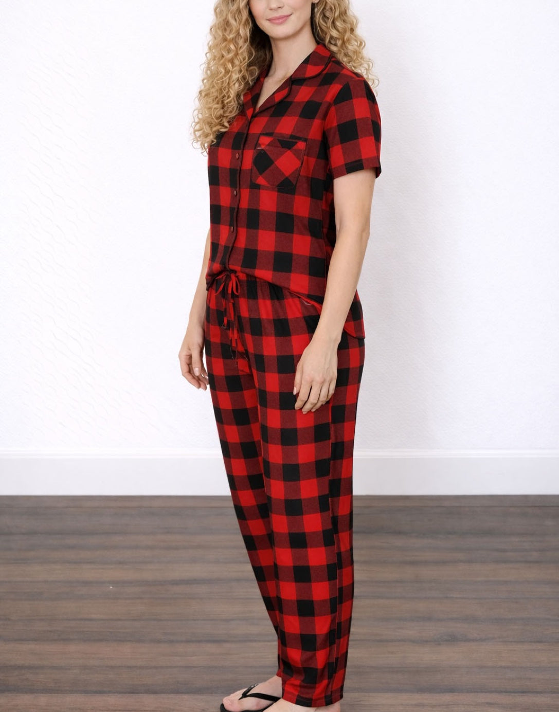 Side view of woman wearing matching red and black checkered pajama shirt and pajama pants set.