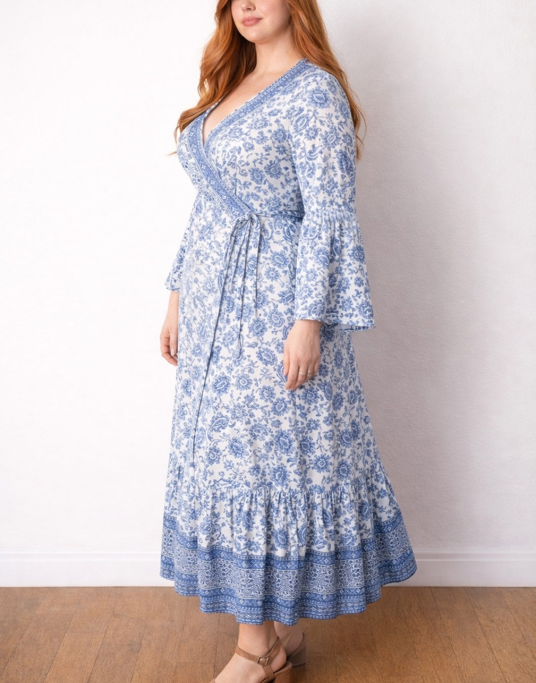 Side view of woman wearing a blue floral Plus Size Bell Sleeve Wrap Maxi Dress against a white background.
