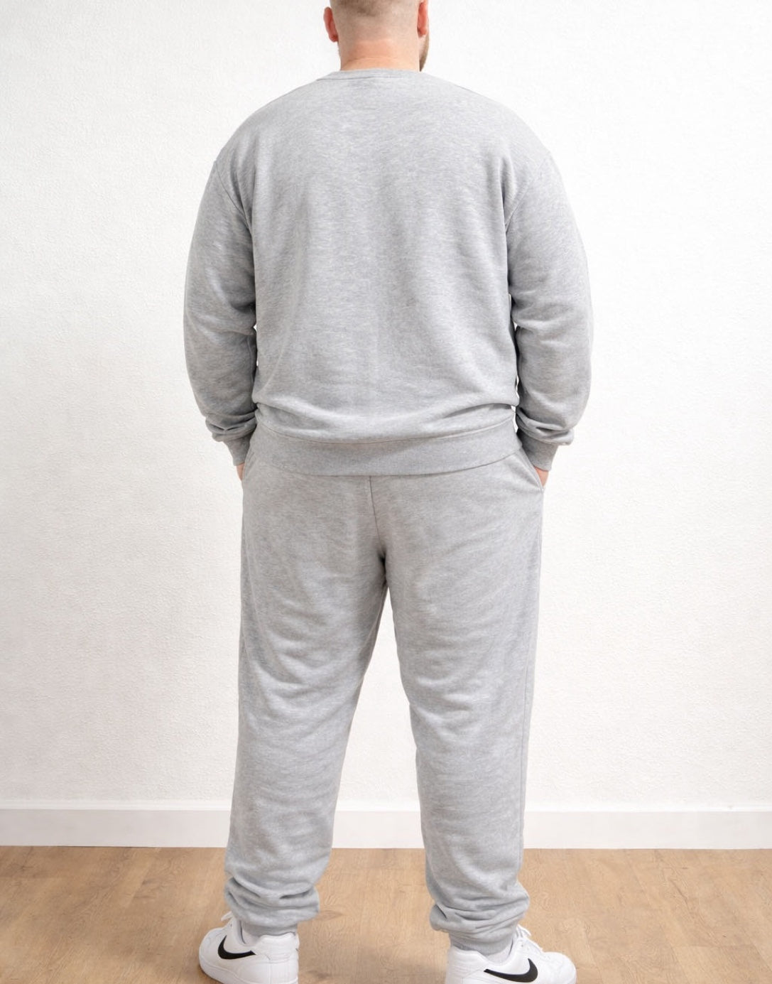 Back view of person wearing a gray tracksuit with Plus Size Drawstring Jogger Pants and white sneakers on a plain background.