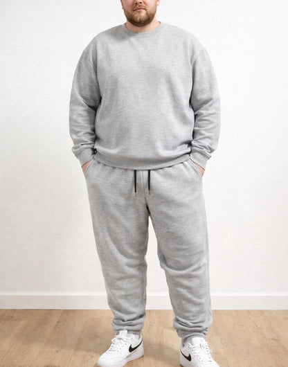 Person wearing a gray tracksuit with Plus Size Drawstring Jogger Pants and white sneakers on a plain background