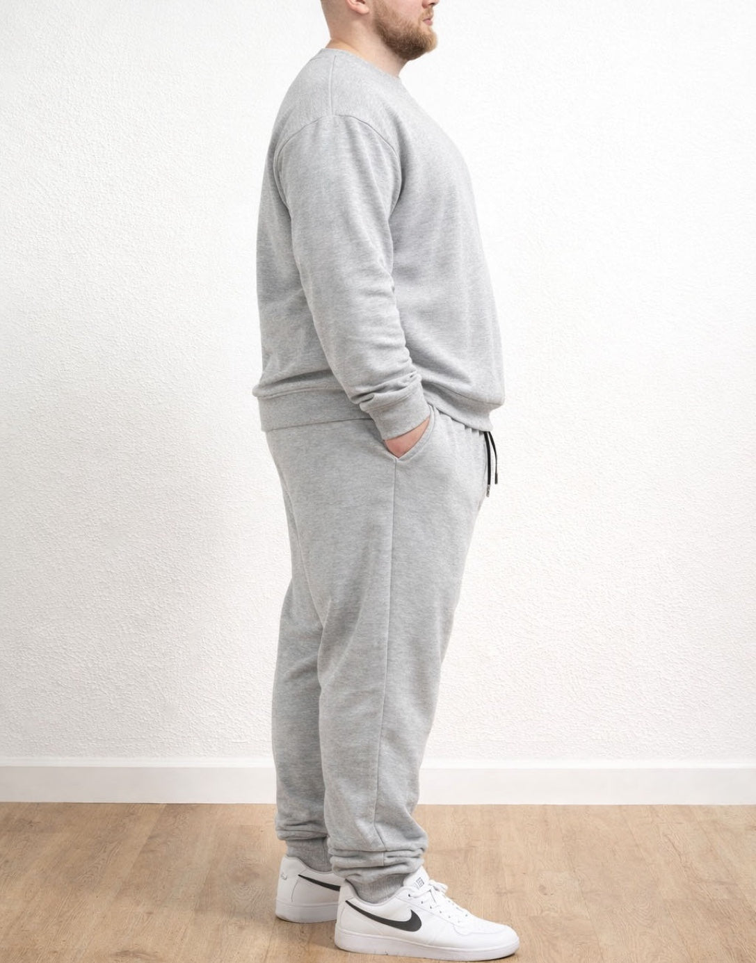 Side view of person wearing a gray tracksuit with Plus Size Drawstring Jogger Pants and white sneakers on a plain background.