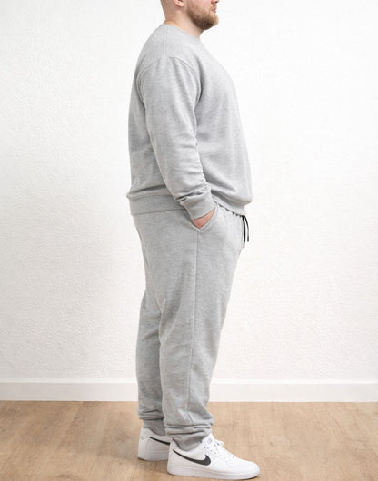 Side view of person wearing a gray tracksuit with Plus Size Drawstring Jogger Pants and white sneakers on a plain background.