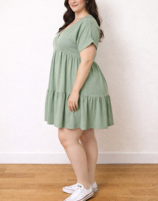 Side view of woman wearing a green Plus Size Gathered Smock Dress standing against a plain background.