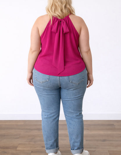 Back view of woman wearing a pink Plus Size Halter Top and blue jeans on a white background