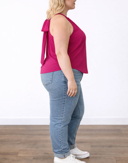 Side view of woman wearing a pink Plus Size Sleeveless Top and blue jeans on a white background