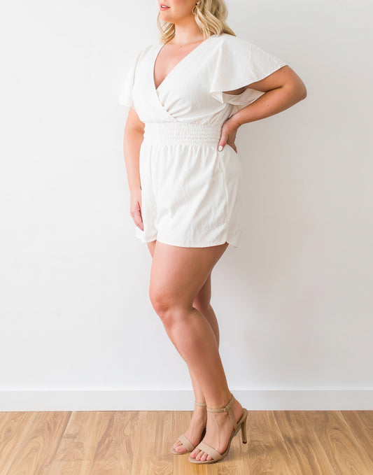Side view of woman wearing a white Plus Size Kimono Sleeve Surplice Romper against a plain background.