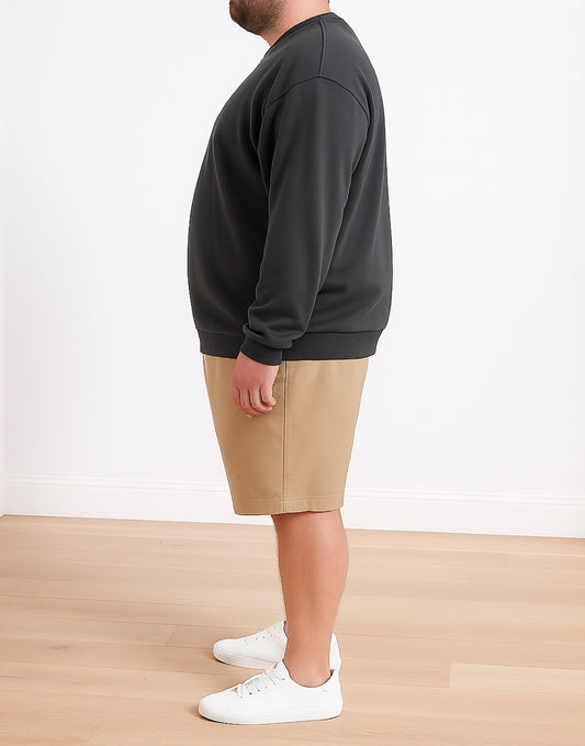 Side view of person wearing a dark gray Plus Size Mens Classic Sweatshirt, beige shorts, and white sneakers on a plain background.