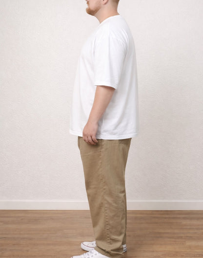 Side view of person wearing a white Plus Size Men Oversized Longline Tee and beige pants against a plain background.