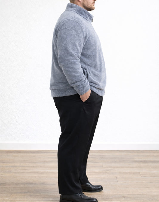 Side view of man wearing a gray Plus Size Mens Bomber Jacket and black pants standing against a white wall.