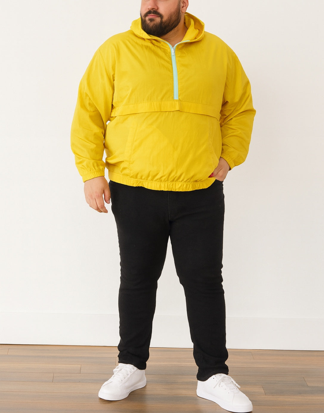 Person wearing a yellow Plus Size Mens Windbreaker Jacket with zipper, black pants, and white shoes on a white background.