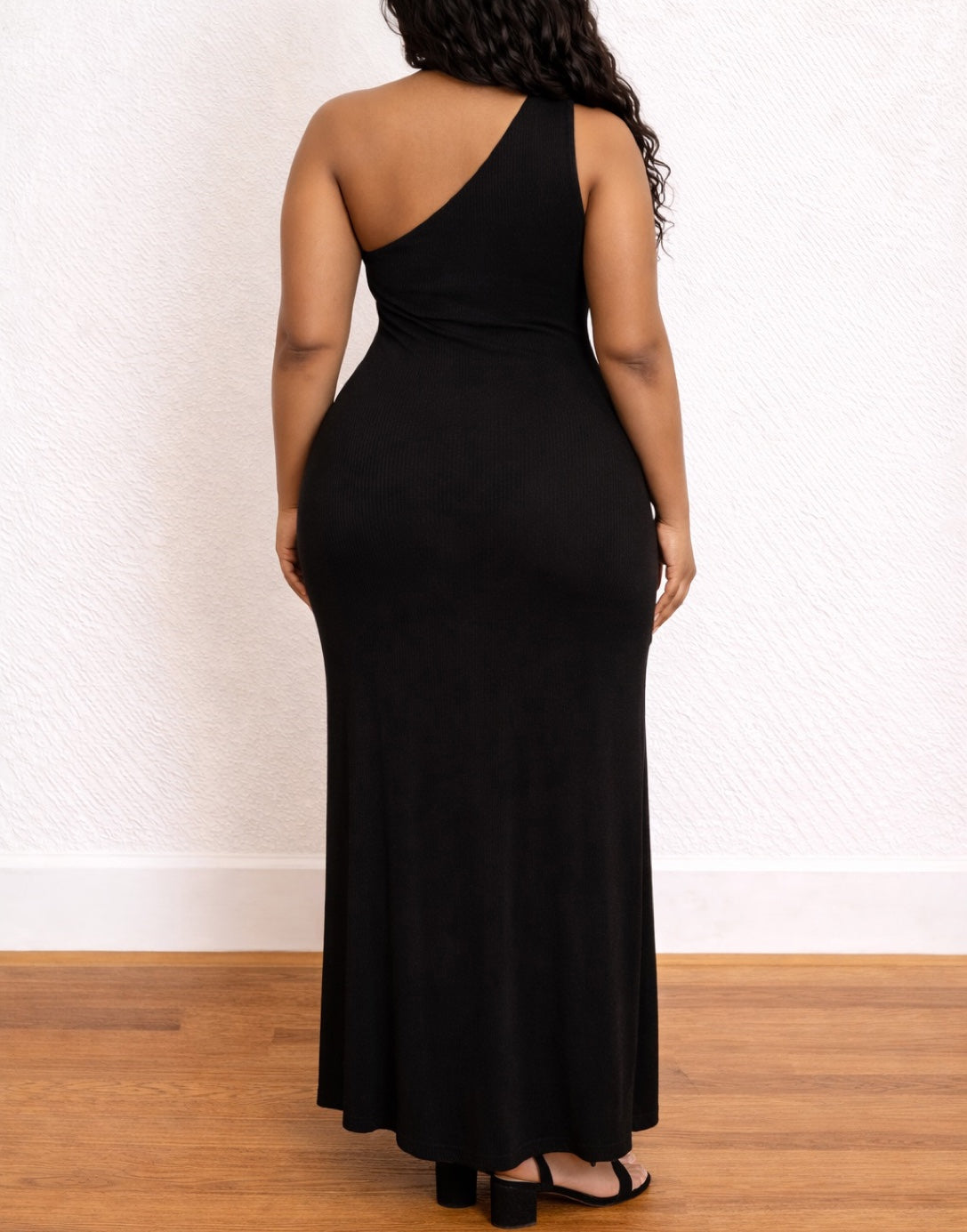 Back view of woman wearing a black Plus Size One Shoulder Maxi Dress on a white background.