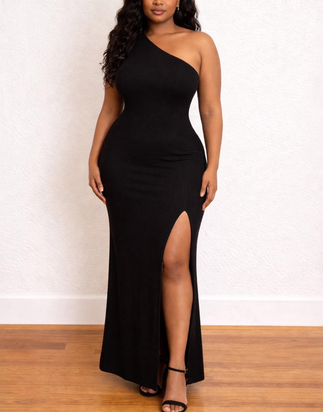 Woman wearing a black Plus Size One Shoulder Maxi Dress with a high slit on a white background