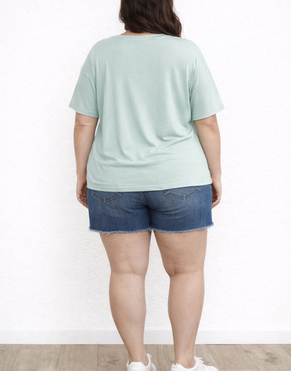 Back view of person wearing a light green Plus Size Oversized Crew Neck T-Shirt and denim shorts on a white background