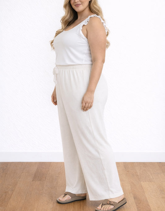 Side view of woman wearing a white sleeveless top and Plus Size Palazzo Pants on a wooden floor.