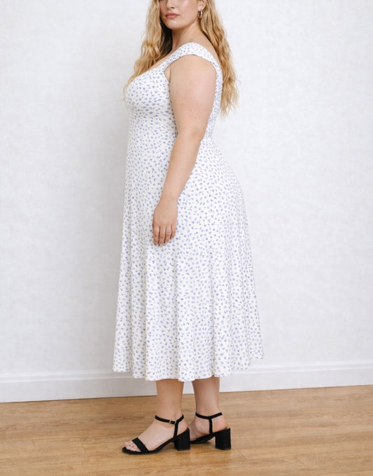 Side view of woman wearing a white Plus Size Midi Dress with a sweetheart neckline and cap sleeves in a room with plain background..