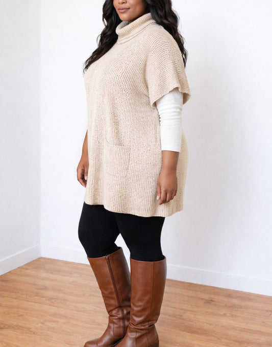 Side view of woman wearing a beige Plus Size Turtleneck Pocket Sweater Tunic Dress over a white long sleeve shirt with black leggings and brown knee-high boots..