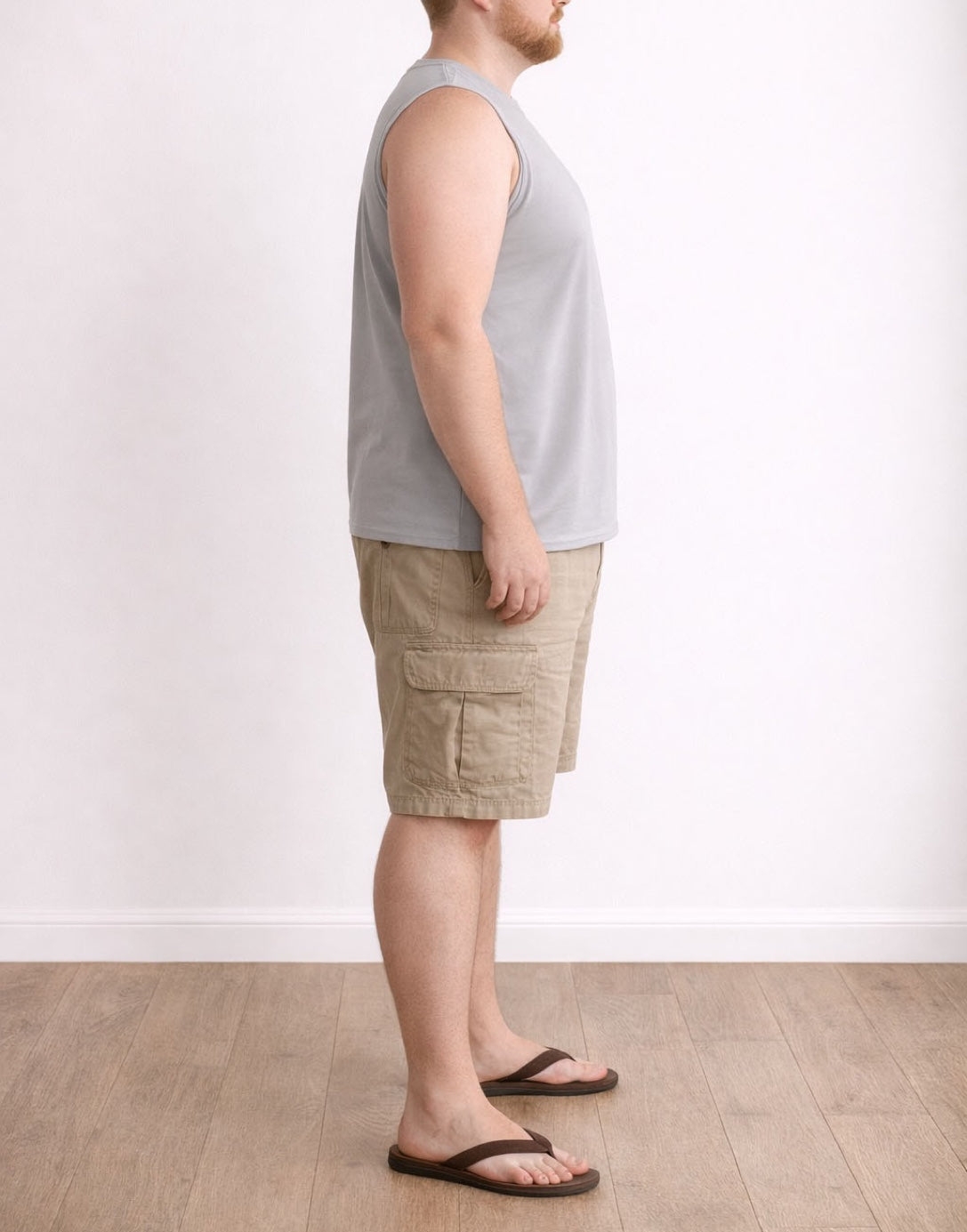 Side view of person wearing a light gray Plus Size Sleeveless Shirt and beige cargo shorts on a white background.