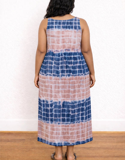 Back view of woman wearing a tie-dye Plus Size Tank Dress with blue and pink patterns against a white wall.