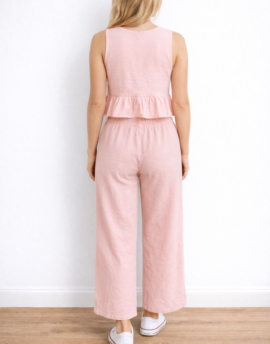 Back view of woman wearing a pink Ruffle Hem Crop Top and pants set on a white background.