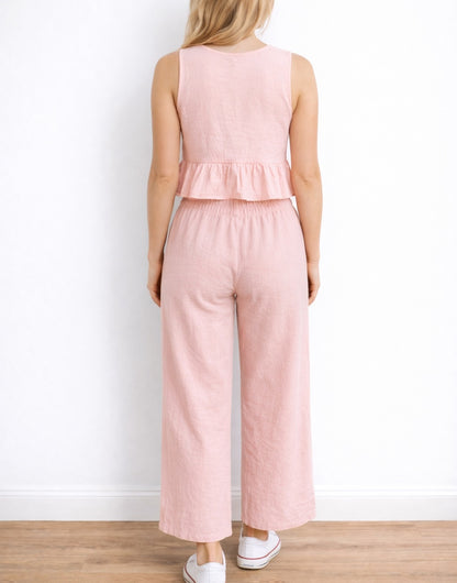 Back view of woman wearing a pink Ruffle Hem Crop Top and pants set on a white background.