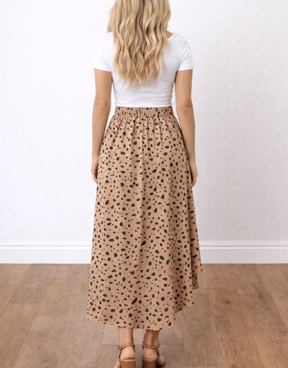 Side voew of woman wearing a white top and patterned Ruffle Midi Skirt on a plain background. 