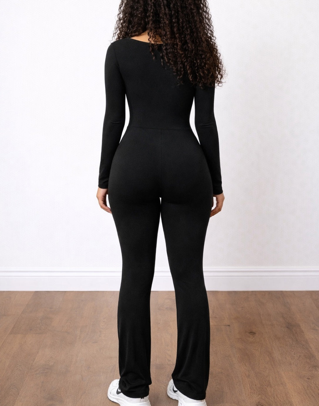 Back view of woman wearing a black Square Neck Flare Leg Jumpsuit against a plain background.