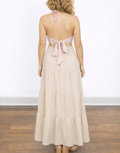 Back view of woman wearing a Tie Backless Halter Top and long beige skirt on a white background.