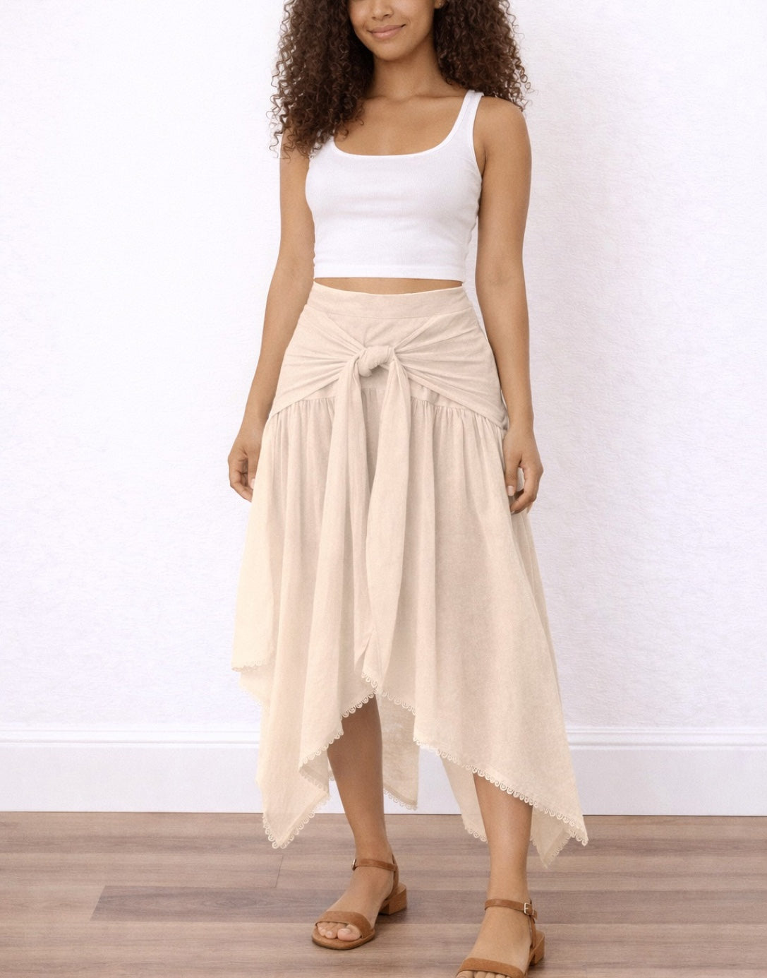 Woman wearing a white top and beige Tie Front Asymmetrical Hem Skirt on a plain background