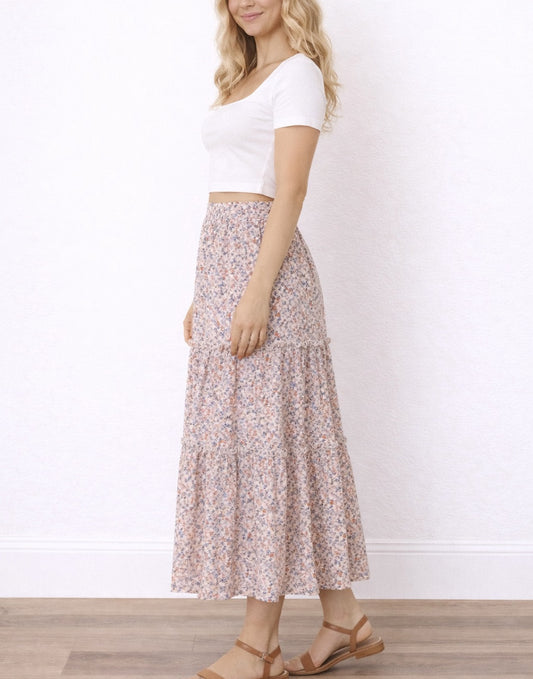 Side view of woman wearing a white top and floral Tiered Ruffle Hem Maxi Skirt against a plain background.