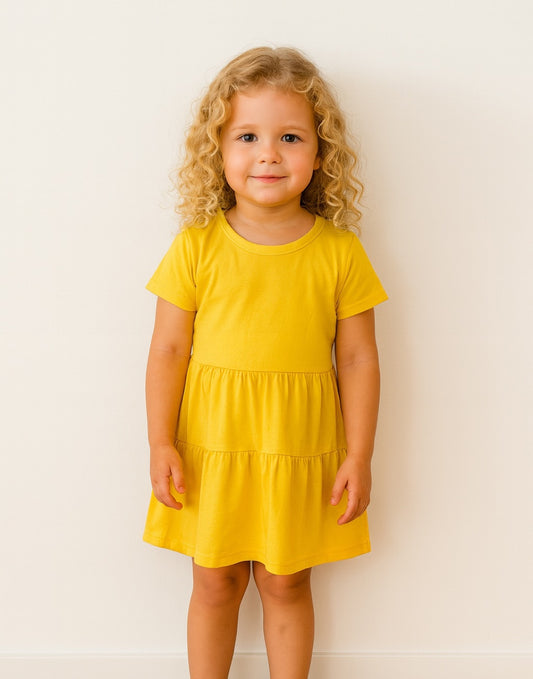Young girl wearing a yellow Ruffle Hem T-Shirt Dress against a white background