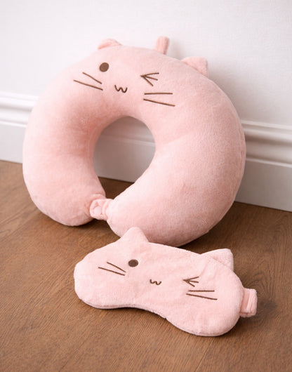 Side view of pink cat-shaped Travel Pillow and Eye Cover on a wooden floor.