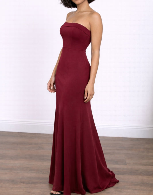 Side view of woman wearing a burgundy strapless Tube Mermaid Maxi Prom Dress on a white background.