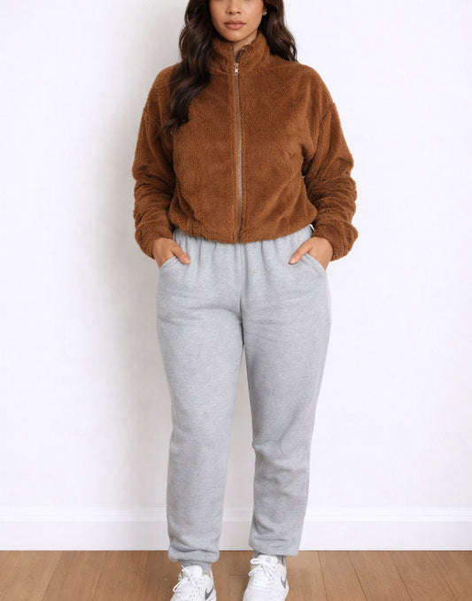 Woman wearing a brown zip-up Bomber Crop Jacket and gray sweatpants on a white background