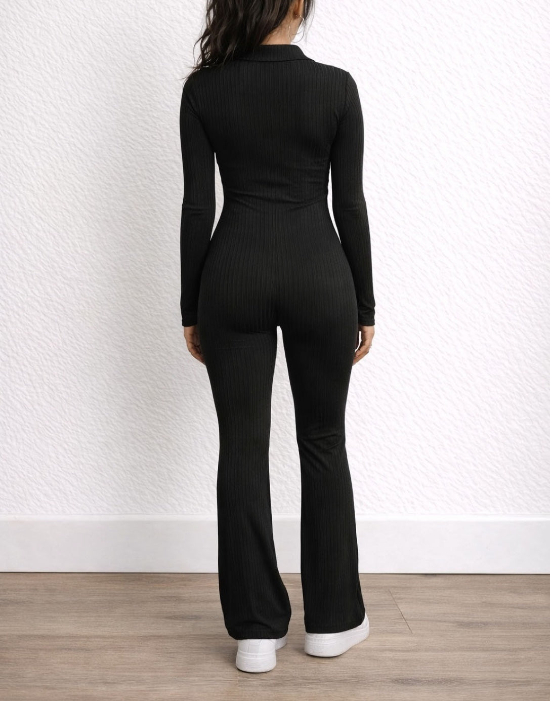 Back view of woman wearing a black Flare Leg Jumpsuit with a white background.